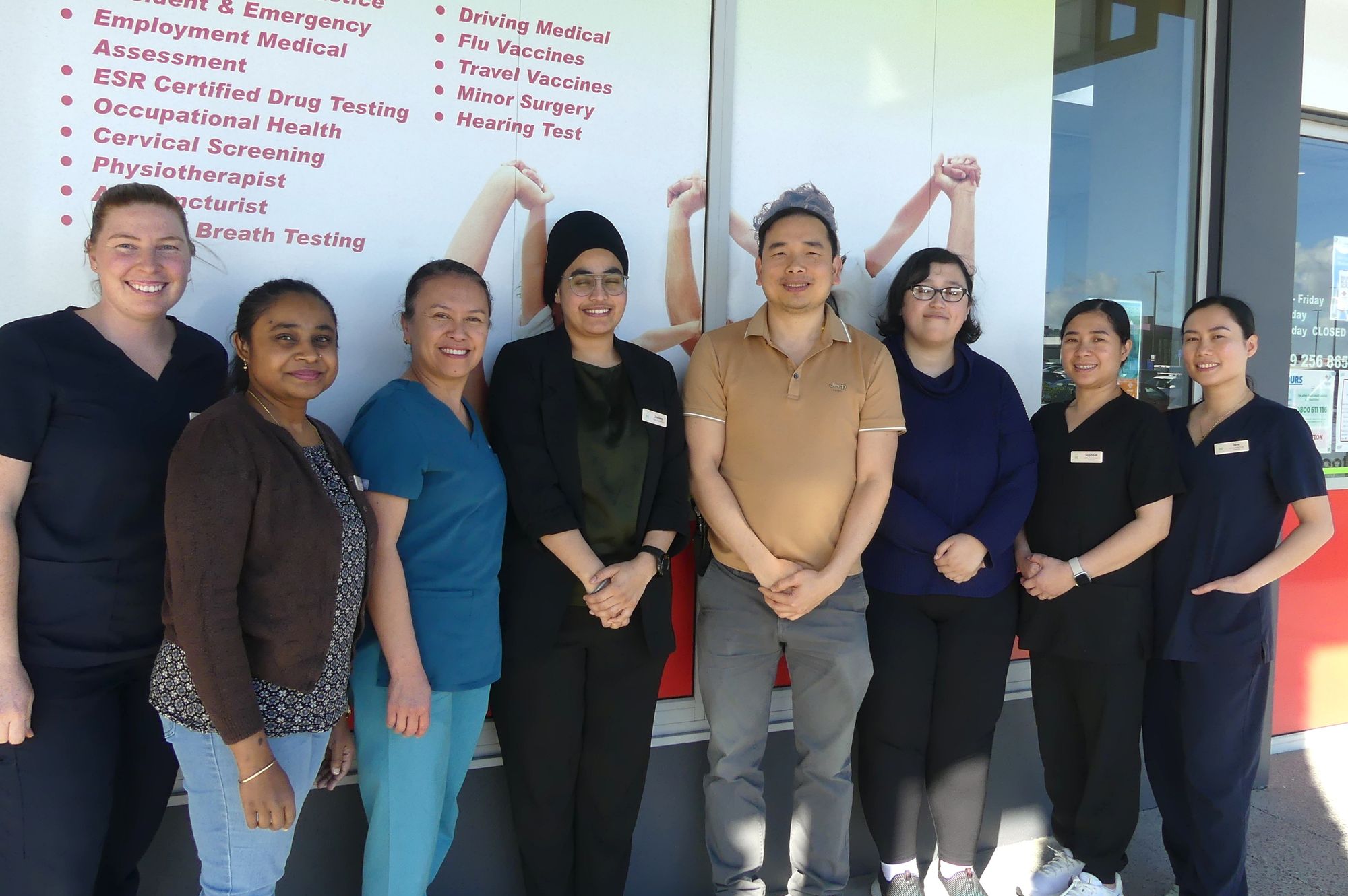The whole team smiling together outside the clinic